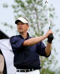 Man wearing golf clothing swinging golf club