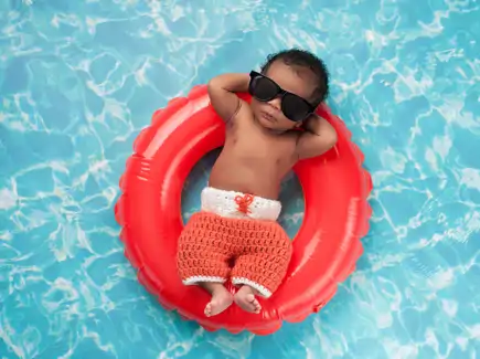 Small boy with sunglasses on a innertube in a pool